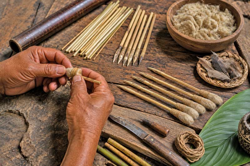 Handcrafted blowgun darts being assembled with natural fibers and reed shafts